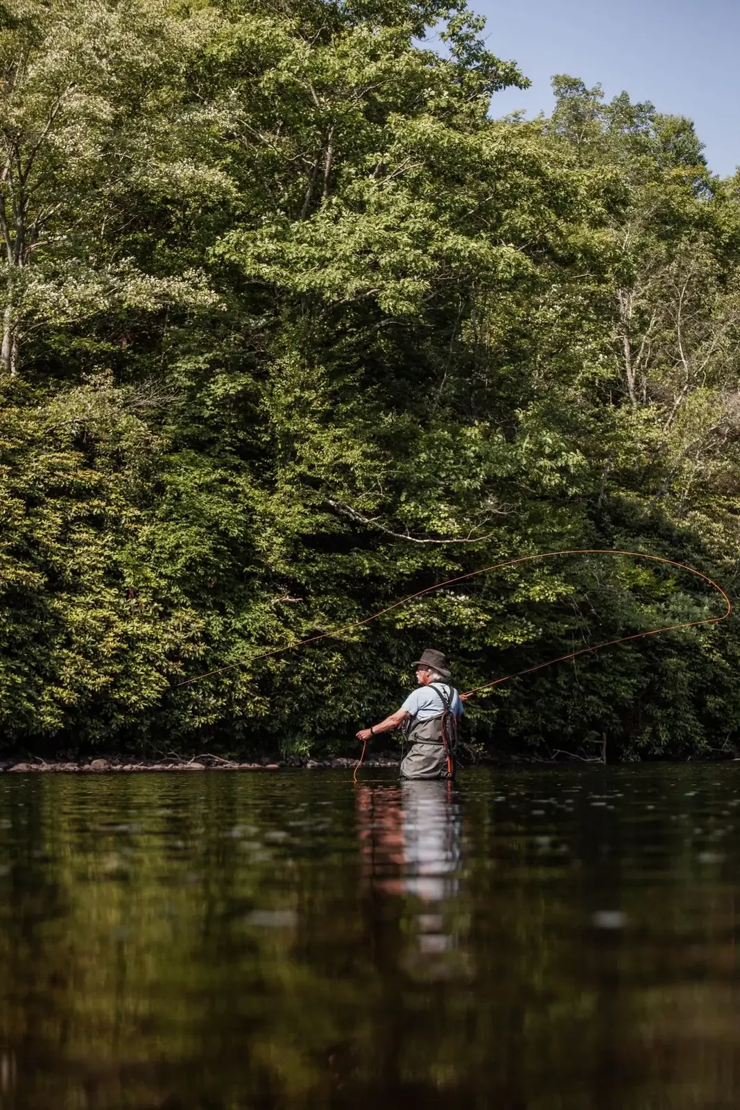 Angler standing in calm wooded water